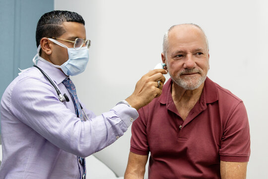 Doctor using ear thermometer on middle-aged patient