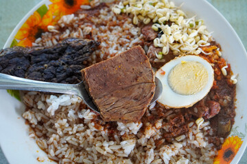 Madura-style rawon with rich black beef soup, tender sliced beef, savory kluwek broth, served with rice, bean sprouts, salted egg, and bold traditional Indonesian flavors