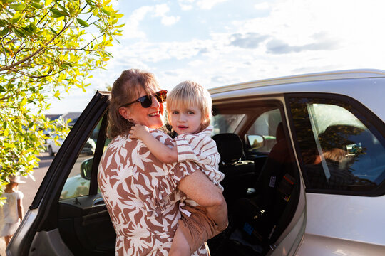 Middle aged Australian woman helping grandchild get into car seat to go to preschool