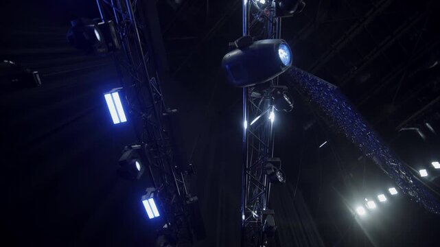 Powerful lighting equipment system on frame over stage low angle shot. Bright spotlights glow illuminating music show in festival hall