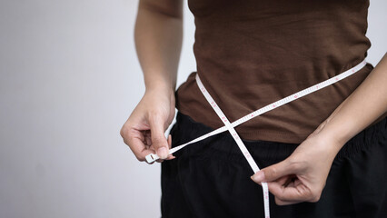 Woman Measuring Her Waist with White Tape Measure for Weight Loss and Fitness Concept