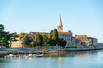 Obraz premium Scenic view of Poreč old town with historic buildings, church tower and small marina along the Adriatic Sea on a sunny day at winter 