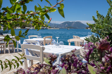 Served tables in a Greek tavern in Vathy Harbor, Meganisi island, Ionian Sea, Greece during the summer tourist season. 