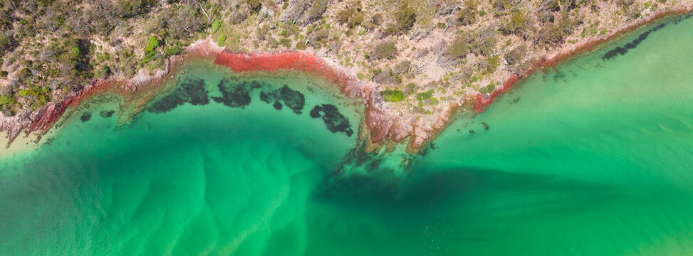 Aerial panorama view of a coastal river bank with rocks covered in colorful lichen