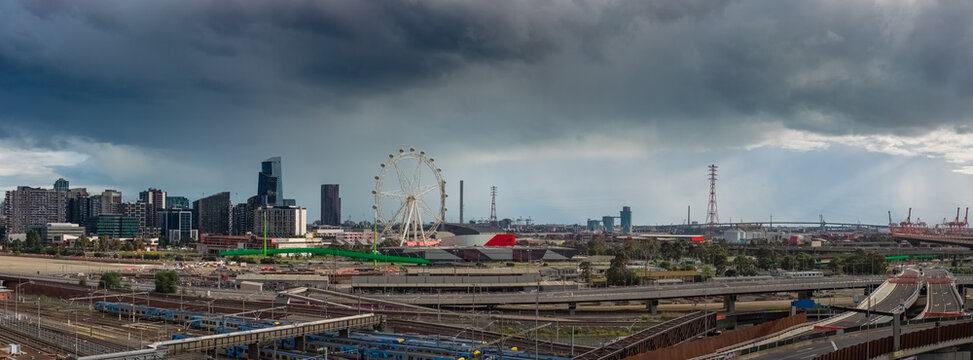 Aerial panorama view of dark clouds over freeways, trains and railway lines on the edge of a city