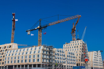 Construction site with a towering cranes and modern buildings under a blue sky