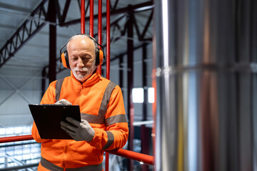 Senior factory worker performing safety inspection wearing ppe