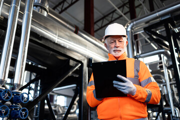 Senior industrial worker checking pipes in factory