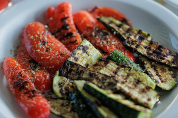 peperoni e zucchine a fette, su un piatto bianco, conditi con spezie miste