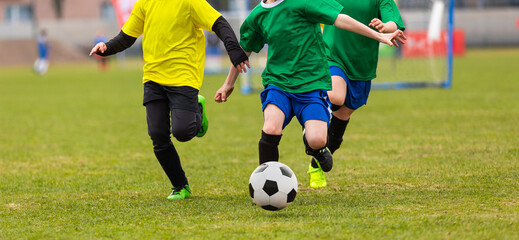 Football school. Happy kids compete in football game. Young boys playing soccer game. Kids having fun in sport. Running soccer players. Competition between players running and kicking football ball