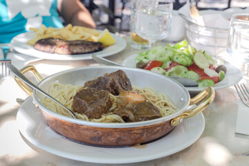 Stewed beef with pasta in a bowl on the table close-up