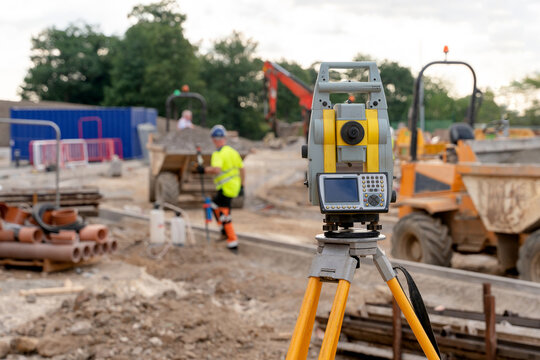 Close-up of Construction survey equipment in use at a building site with builders working in background
