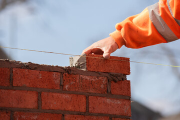 Industrial bricklayer laying bricks and concrete blocks on cement mix mortar on construction site