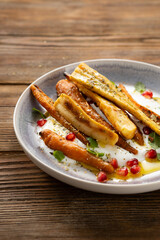 Roasted carrots and parsnips with greek yogurt on plate wood surface