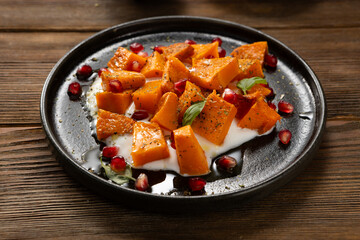 Sliced roasted butternut pumpkin with greek yogurt on plate wood surface