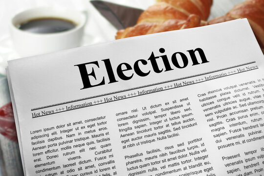 Election in newspaper layout on a breakfast table with a blurry cup of coffee and croissants in the background.