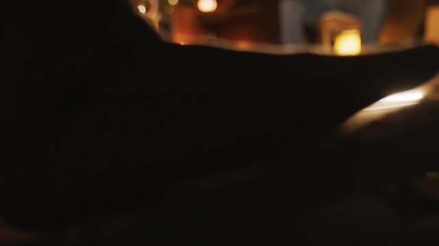 Low angle static close-up of foot engaging a guitar pedal in warm bokeh light.