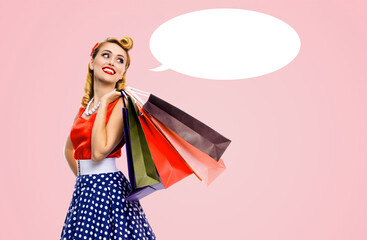 Black Friday Sales concept - beautiful cute blond woman in pinup pin-up dress holding carrying colourful shopping bags isolated rose pink background with empty mockup speech bubble. Mock up ad image