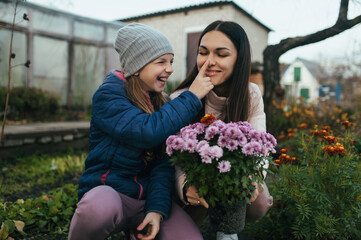 Happy woman mother and beautiful teenage girl daughter laughing sitting in the garden with a bouquet of fresh flowers.