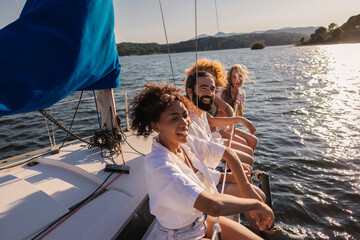 Diverse friends enjoying sailing trip on lake during summer vacation © PintoArt