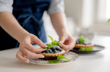 Girl Decorating Blueberry Dessert With Mint Leaves