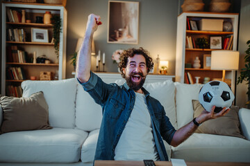 Man celebrating football victory watching game at home