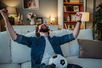 Excited man cheering soccer match celebrating goal at home
