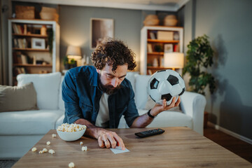 Man holding soccer ball watching game and betting ticket