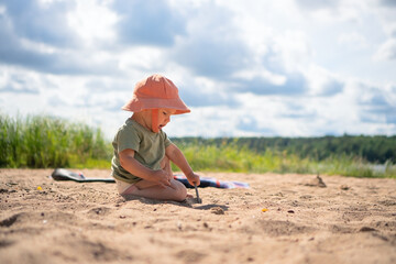 A toddler plays on a sandy beach wearing an orange hat, enjoying the warmth and freedom of outdoor play.