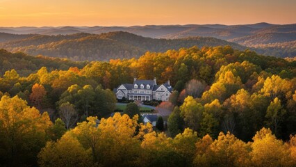 A large stately home nestles among vibrant fall foliage in rolling hills at sunset
