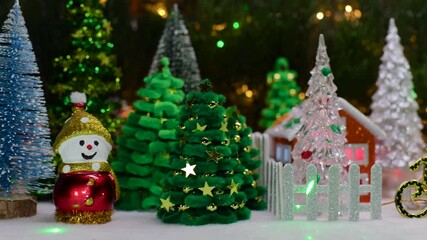 Two houses and a snowman on a sled and Christmas trees behind a fence surrounded by Christmas trees and snowmen with a gnome