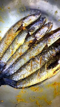 Ikan bumbu kuning or marinated fish on bowl. Cooked with herbs spices such as turmeric, lemon grass, garlic, coriander, ginger, lime leaves, candle nuts. Ready to be fried.