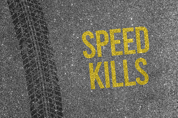 Tire track on asphalt background with yellow text Speed Kills. Road safety and traffic danger concept.