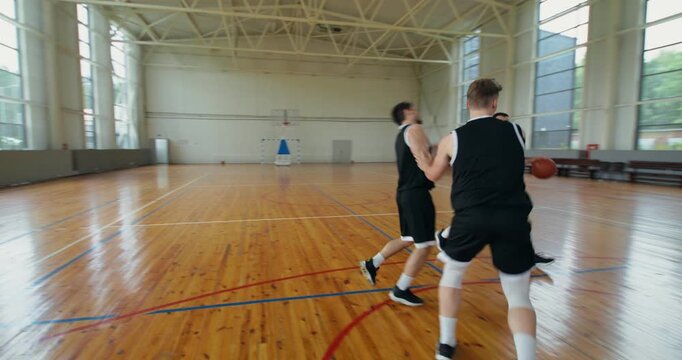 The team players are taking part in a basketball game.. a team of four players play basketball on an indoor court.