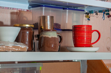 Kitchen shelf with coffee jar, mugs, and storage containers