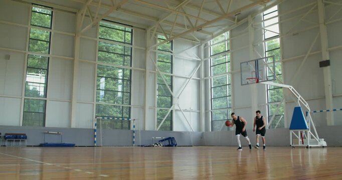 Two players compete in basketball on a basketball court.. two basketball players play basketball with one hoop.