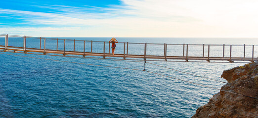 Woman tourist on a suspension bridge enjoying breathtaking sea view, Torrenueva, Granada province in Spain