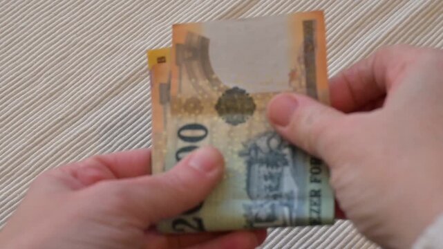 Close-up video of a female hand counting Hungarian forint banknotes on a clean white background. Strong financial concept representing income management, budgeting, salary, expenses control, accountin