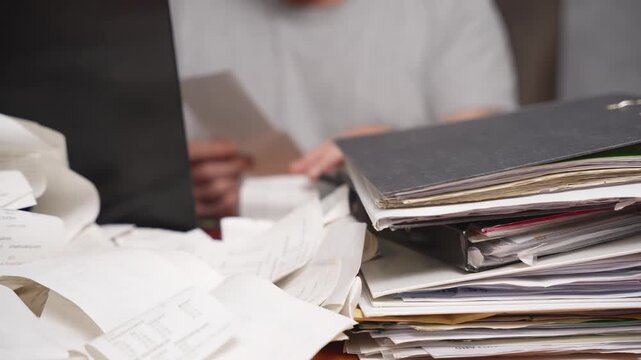 Financial audit and document verification. Close-up of hands examining receipts and documents next to a laptop and folders. The concept of financial audit, tax control, accounting accuracy and complia