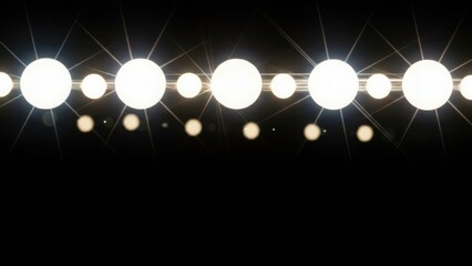 A row of bright glowing stage lights on a black background. Marquee or vanity mirror bulbs with a lens flare effect. Abstract entertainment concept with copy space