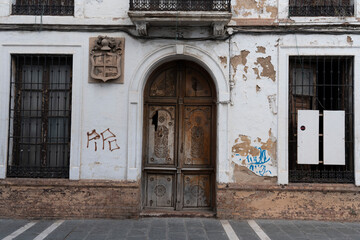 Old building entrance with wooden door and graffiti.. Ronda, M&aacute;laga, Spain