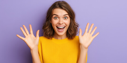 Surprised young woman with open mouth and raised hands expressing excitement and joy against a purple background.