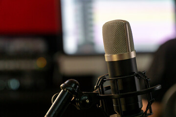 Professional studio condenser microphone on a shock mount with blurred musical instruments in the...