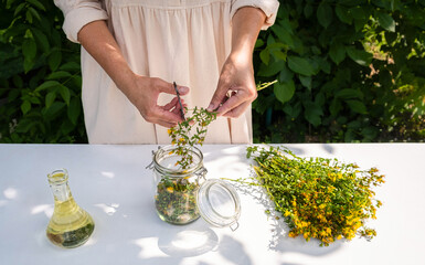 St. John's Wort Oil Recipe Step 7: Woman Trimming Flowers into Jar