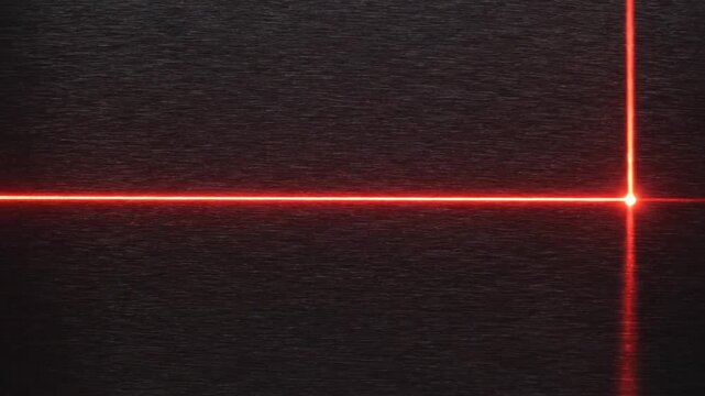 A bright red laser crosshair forms a perfect right angle against a dark, horizontally textured surface, highlighting precision and measurement.