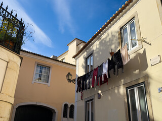 Residential buildings with balconies and hanging clothes in a narrow street of Lisbon Portugal