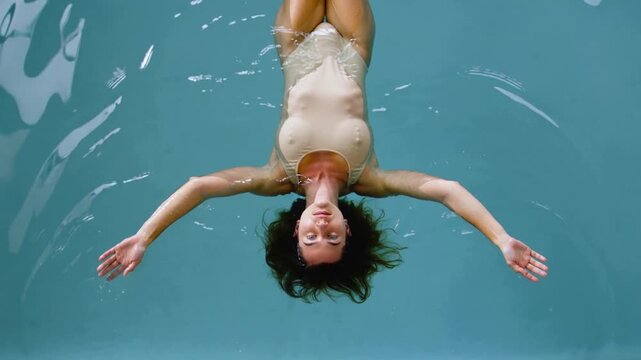Swimming under water in a pool with a woman floating on her back