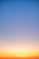 Sunset or sunrise sky with a vibrant gradient of orange, gold, and soft blue. Clear atmosphere with wispy clouds. Peaceful, natural light background. hope, freedom, new day Concepts, Vertical