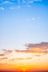 Sunset or sunrise sky with a vibrant gradient of orange, gold, and soft blue. Clear atmosphere with wispy clouds. Peaceful, natural light background. hope, freedom, new day Concepts, Vertical