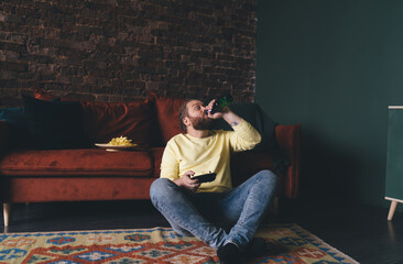Man drinks beer while gaming, controller in hand © BullRun